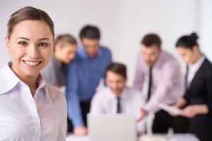 Business meeting - manager discussing work with his colleagues. closeup on woman standing on foreground with crossed hands and team on background